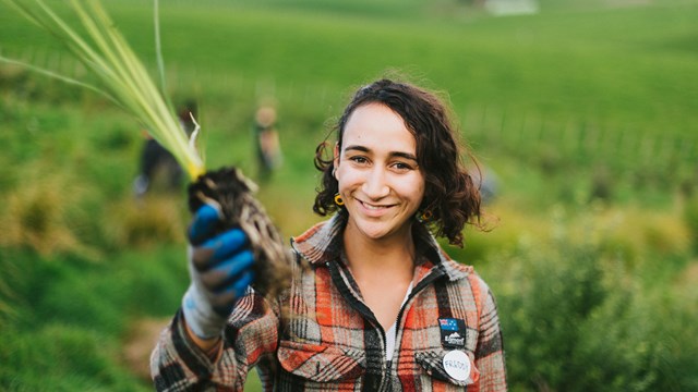 Woman holding native seedling up to the camera